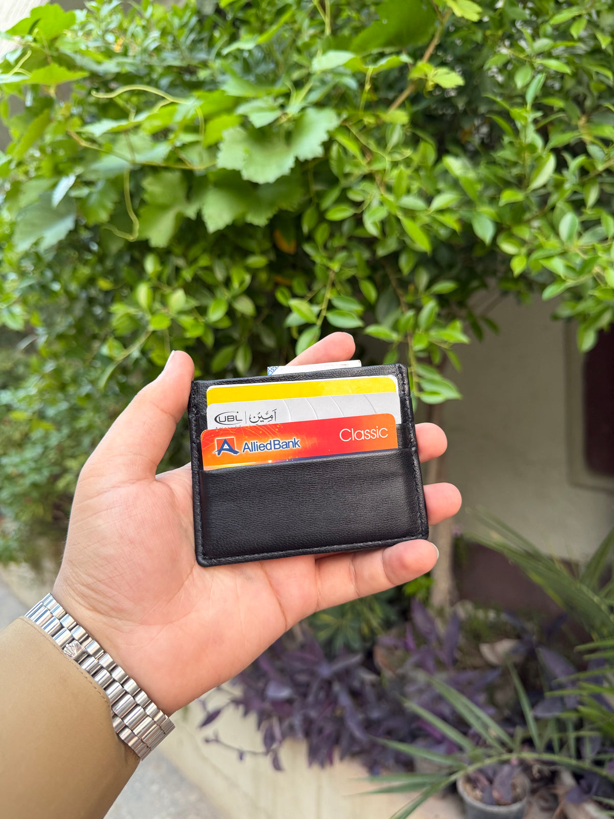 Black Slim Card Holder outdoor front view with multiple cards loaded showing UBL and Allied Bank cards